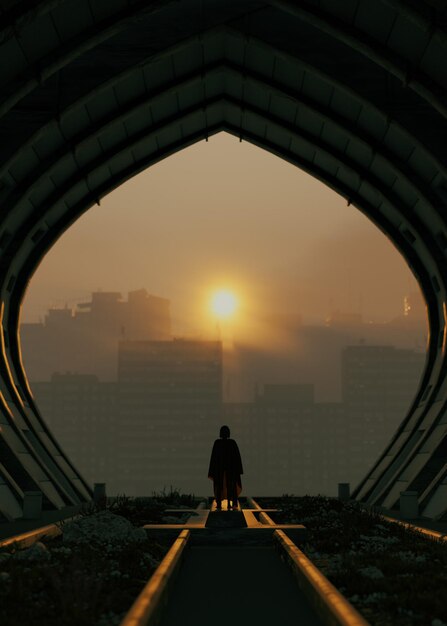 Photo a man stands in a tunnel with the sun behind him.