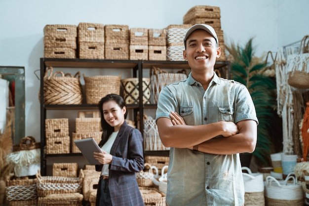 Man stands with crossed hands among handicraft items on a casual woman's  using a tablet in a craft gallery