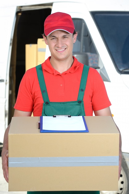 A man stands with a parcel and smiles.