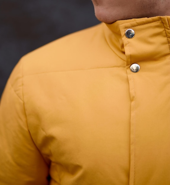 Man stands in yellow winter jacket on grey background