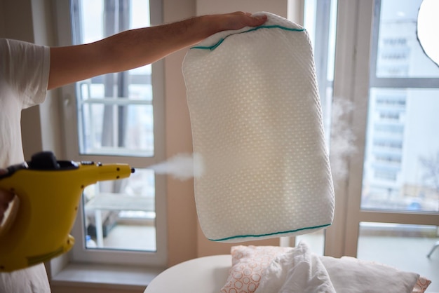 Man steaming pillow at home closeup view