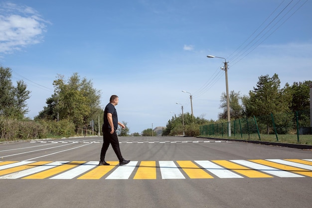 Man steekt de straat over langs felgele rijstrookmarkeringen op het zebrapad op het platteland