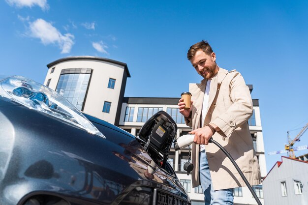 Man steekt stekker in het oplaadcontact van elektrische mobiel