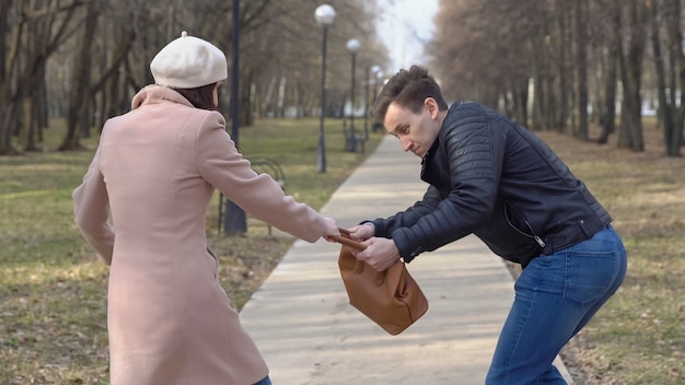 Man steelt de tas van een vrouw van een bankje in het park.