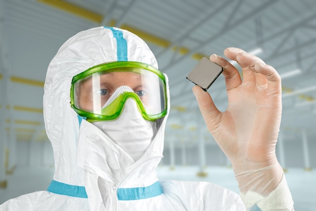 Man in sterile form holds a microprocessor in his hands, closeup