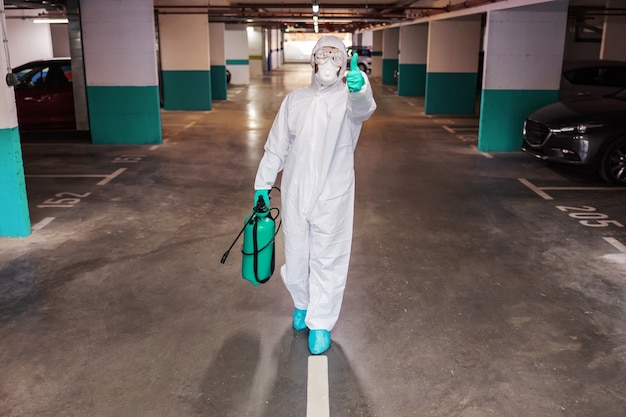 Man in sterile suit disinfecting hall of the building. Protection from corona concept.