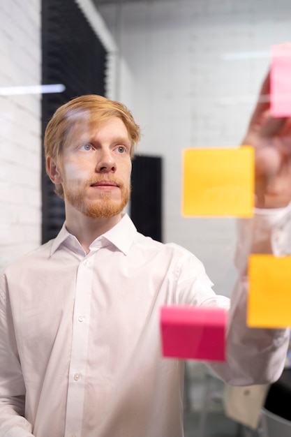 Photo man sticking post it on window medium shot