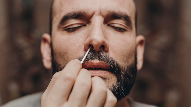 Man sticks nasal swab in nose of covid antigen test in foreground