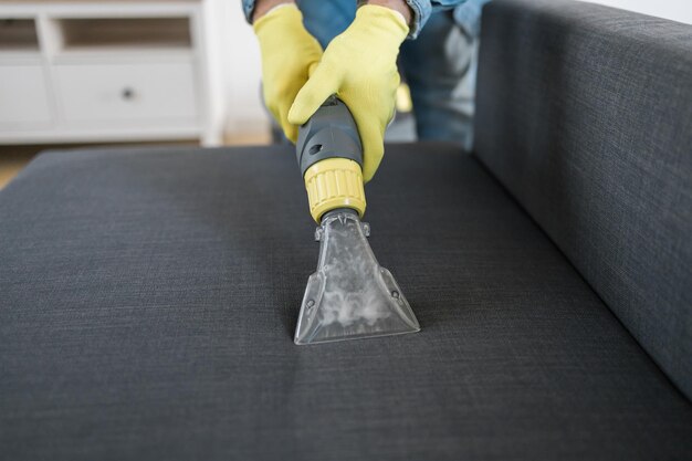 Man stomerijen werknemer dient beschermende rubberen handschoen schoonmaak bank met professioneel extracti