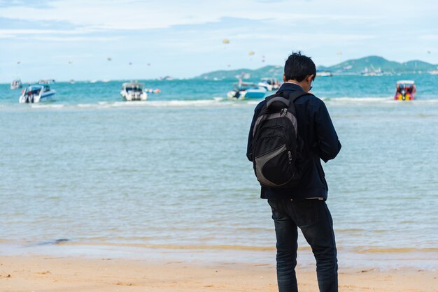 A man stood waiting for a boat ride on the beach.