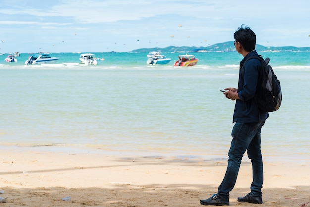 A man stood waiting for a boat ride on the beach.