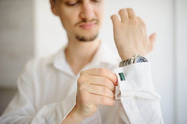 A man straightens cufflinks on a shirt. Close-up.