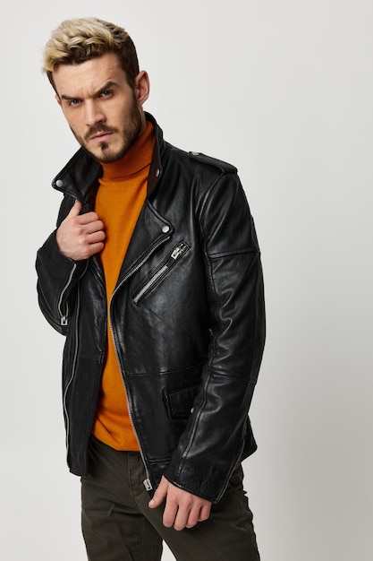 Man straightens leather jacket orange sweater pants fashion style