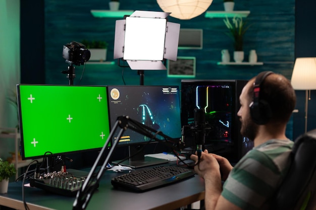 비디오 게임을 스트리밍하고 수평 녹색 화면을 사용하는 남자. 컴퓨터 디스플레이에 격리된 모형 템플릿이 있는 크로마 키가 있는 동안 온라인 게임을 하는 사람. 스트리밍 중인 게이머