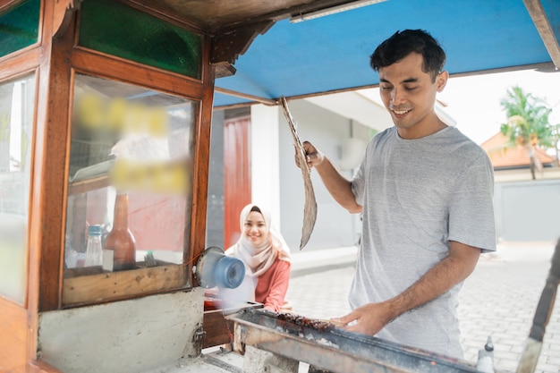 Man street food seller of chicken satay with food cart selling sate ayam