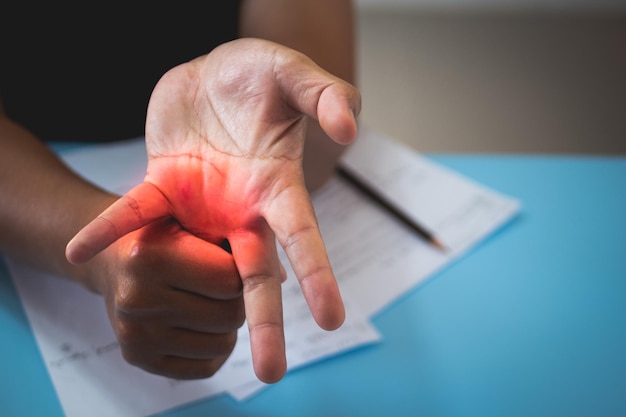 The man stretches his ring finger after he has worked office\
syndrome concept pain symptom area is shown with red color close up\
shot