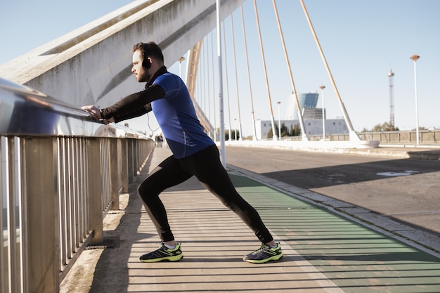 Man stretching on a bridge railing. sport concept