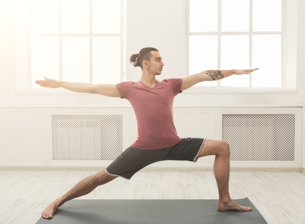 Uomo che allunga mani e gambe sul tappetino in palestra. l'atleta fa allenamento. sport, yoga, pilates, fitness, concetto di stile di vita sano