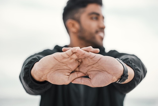 man stretching hands and ready in outdoor for exercise runner and cardio for training or workout male person cloudy sky and athlete preparation for fitness performance and sports for competition