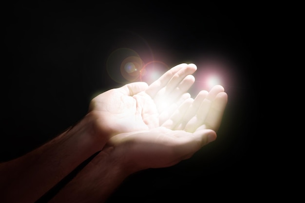 어둠의 근접 촬영 기도 개념에서 빛을 향해 손을 스트레칭 하는 남자