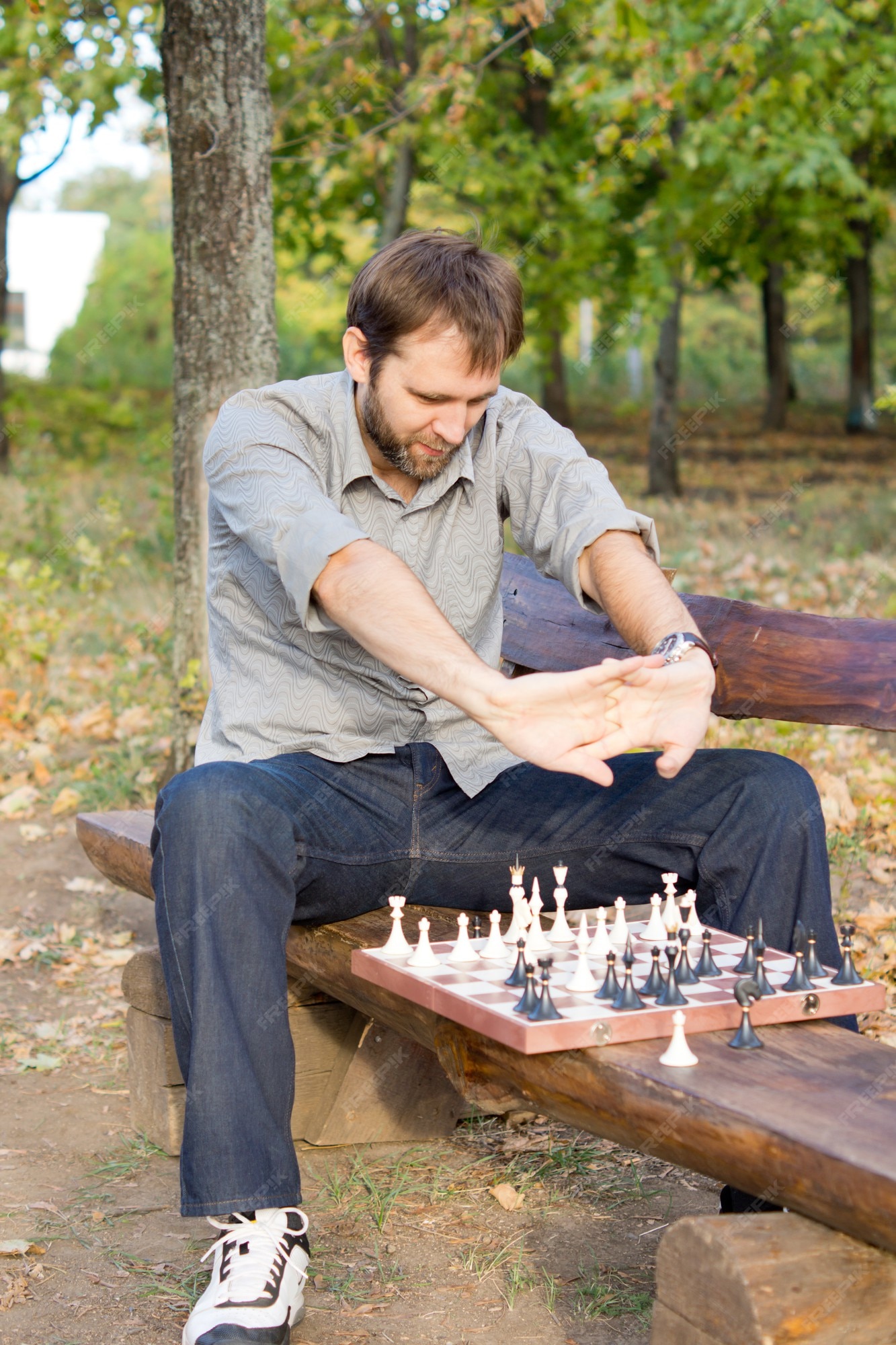 Premium Photo  Young bearded man in sunglasses sitting on a wooden park  bench planning his next chess move