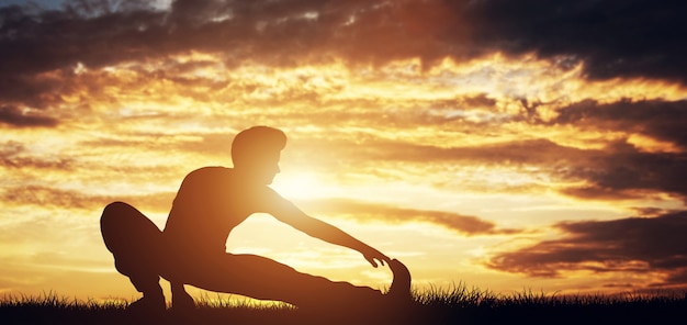 Man stretching his body in the sunset.