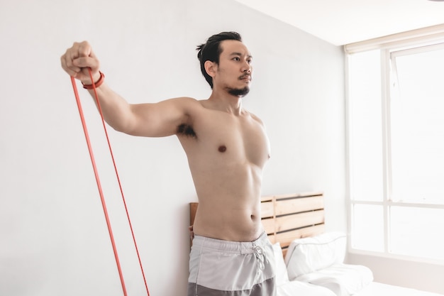 Man stretching his muscle in concept of workout at home with resistance band.