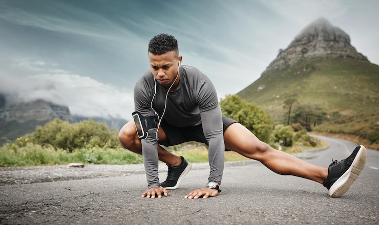Photo man stretching legs and music before exercise fitness and workout on road outdoor male athlete headset and training for health wellness and flexibility with endurance or balance in nature