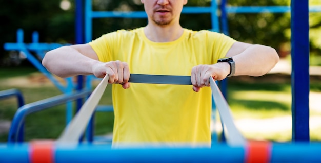Man stretching with elastic rubber during street workout