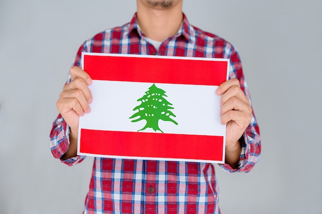 Man in a striped shirt holding the flag of Lebanon.