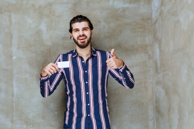 Man in striped shirt holding his business card and enjoying his new position