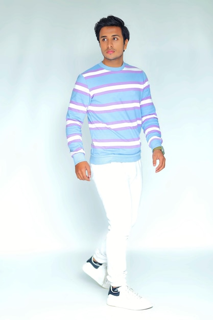 A man in a striped shirt and white pants walks down a white floor.