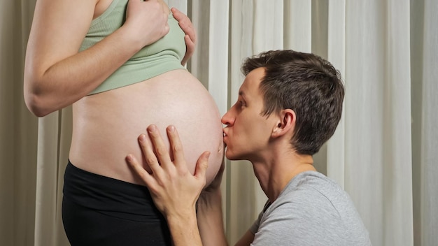 Man strokes and listens to unborn baby in stomach of wife