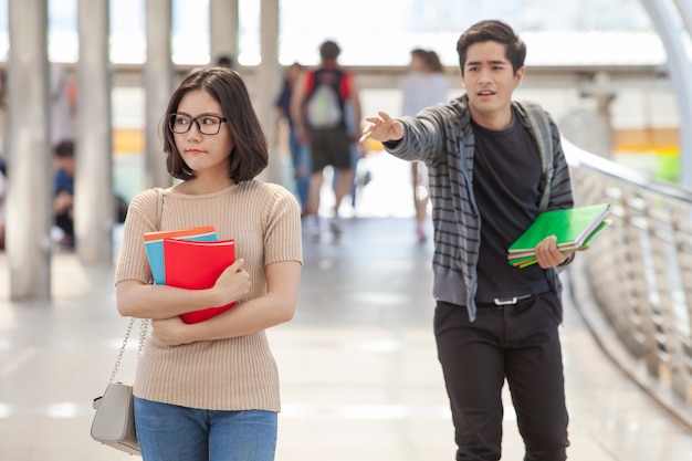 走っている男の学生が手にホルンの本の中で彼の友人に連絡しようとする