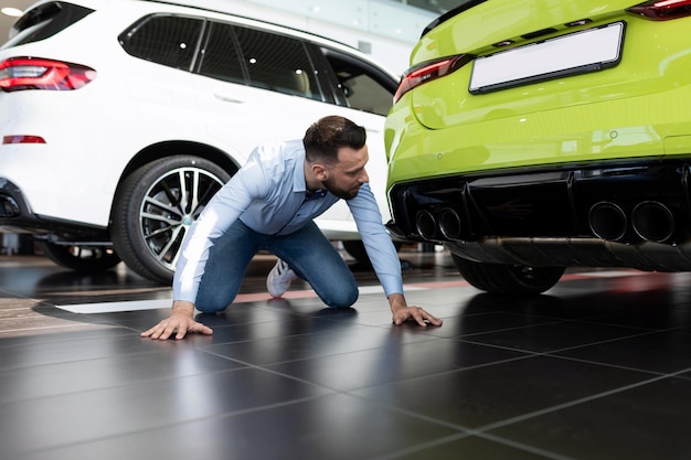 Man studying the features of a new car in the showroom of a car dealership