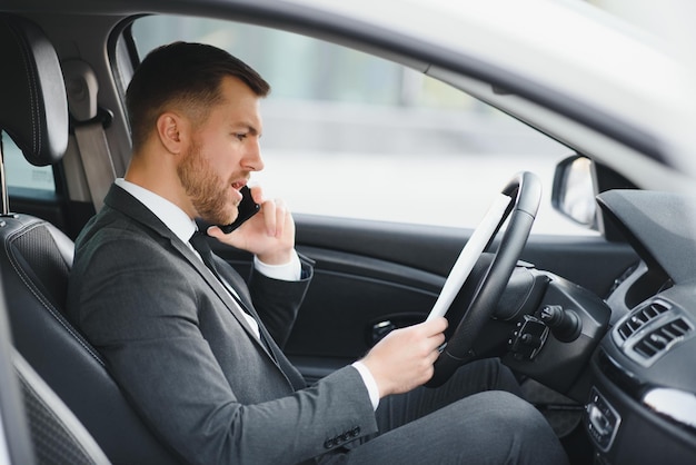 Uomo di stile e status bel giovane in tuta intera sorridente mentre guida un'auto