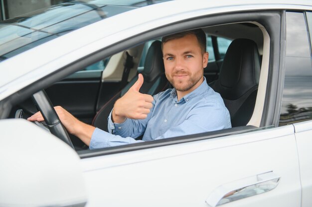 Man of style and status Handsome young man in full suit smiling while driving a car