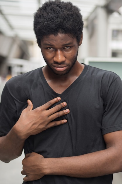 Man suffering from acid reflux or GERD; sick stressed guy with indigestion, acid reflux or gerd symptoms; man health care, body care, sickness, pain concept; adult african man or black man model