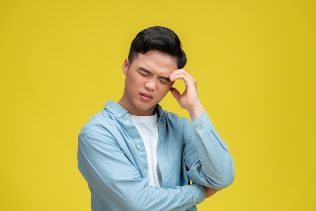 Man suffering from headache or thinking over yellow background