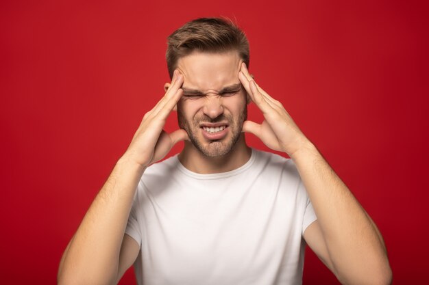 man suffering with headache with closed eyes isolated on red