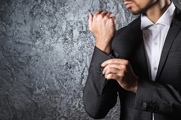 Man in suit buttoning cuff of sleeve