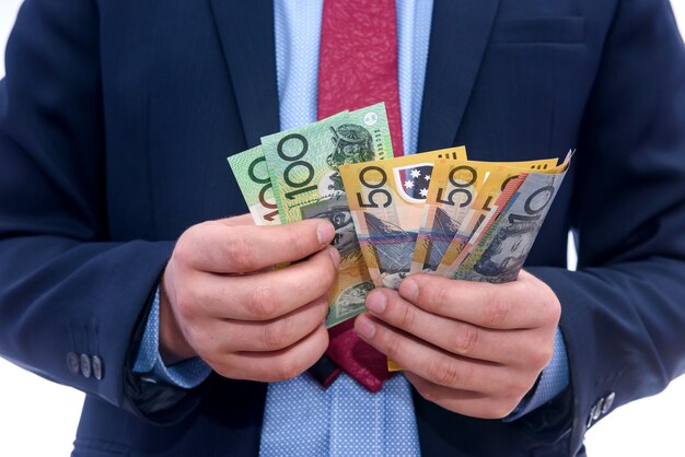 Man in suit counting australian dollar banknotes