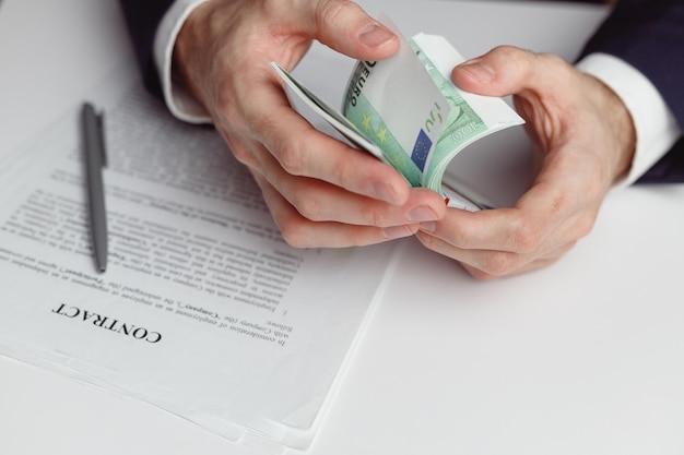 Man in suit counts wad of money before signing contract close up of hands with money