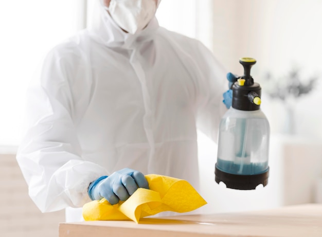 Photo man in suit disinfecting table close-up