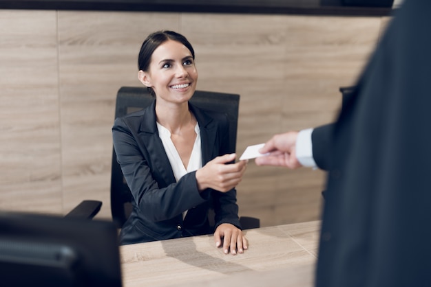 A man in a suit gives his business card to the secretary.