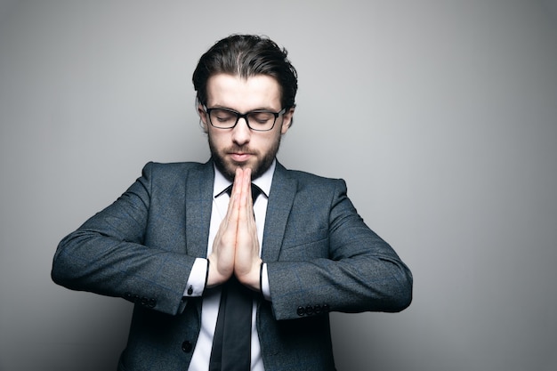 man in suit and glasses joined hands on gray wall