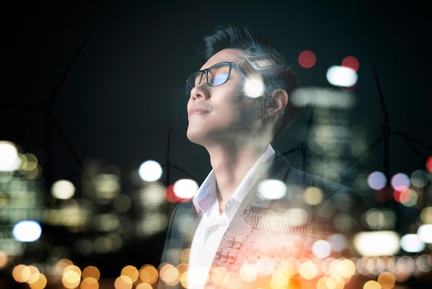 A man in a suit and glasses looks at the city lights.