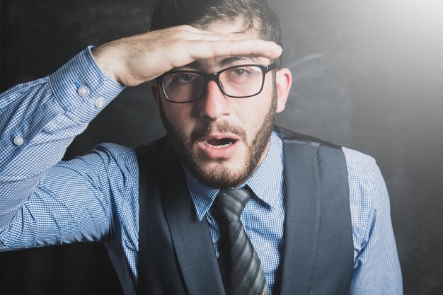 A man in a suit and glasses looks with surprise at a dark foen