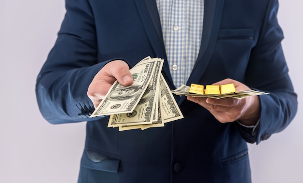 Man in suit hold money dollar bills and gold bar. Business success