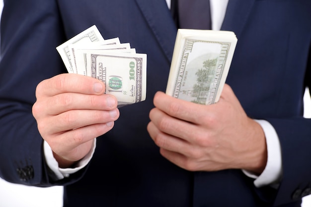 Man in suit holding dollars in his hands.